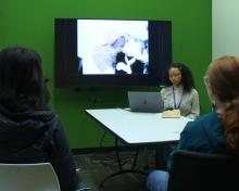 A young woman sits beside her a television sharing her film.