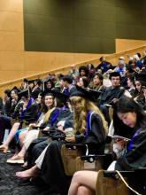 Graduates in academic attire seated in the auditorium waiting for the graduation celebration.