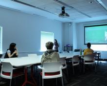 A group of people watch a film projected.