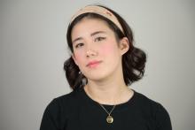 A young women in a t-shirt and gold necklace.