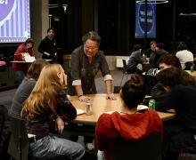 Professor Warren Etheredge shares a friendly chat with a table of five students.