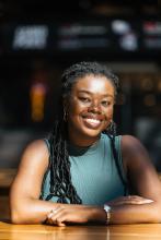 A female sitting at a table smiles at the camera.