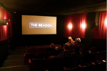A group of people staring at the movie theater screen, which reads, "The Beacon."