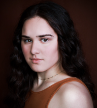 A woman with an orange tank-top and choker style necklace.