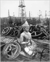 A statue sits among metal cogs.