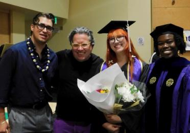 Group of faculty and students come together wearing academic attire at a graduation celebration. 