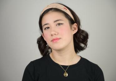 A young women in a t-shirt and gold necklace.