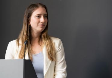 Female instructor stands in front of a classroom.