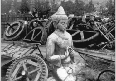 A statue sits among metal cogs.