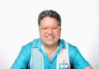 A man smiling in a striped shirt.