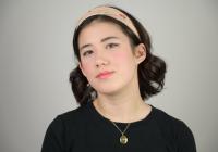 A young women in a t-shirt and gold necklace.