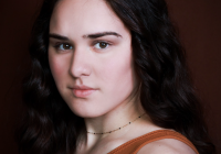 A woman with an orange tank-top and choker style necklace.