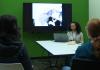 A young woman sits beside her a television sharing her film.