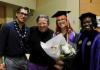 Group of faculty and students come together wearing academic attire at a graduation celebration. 