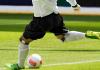 A soccer player kicking a ball. 