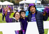 University of Washington student pose behind a white W sign with their family during Family Weekend